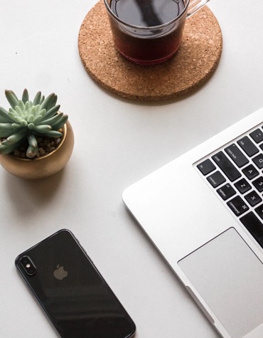 overhead pic of a phone, laptop keyboard, small cactus and coffee cup