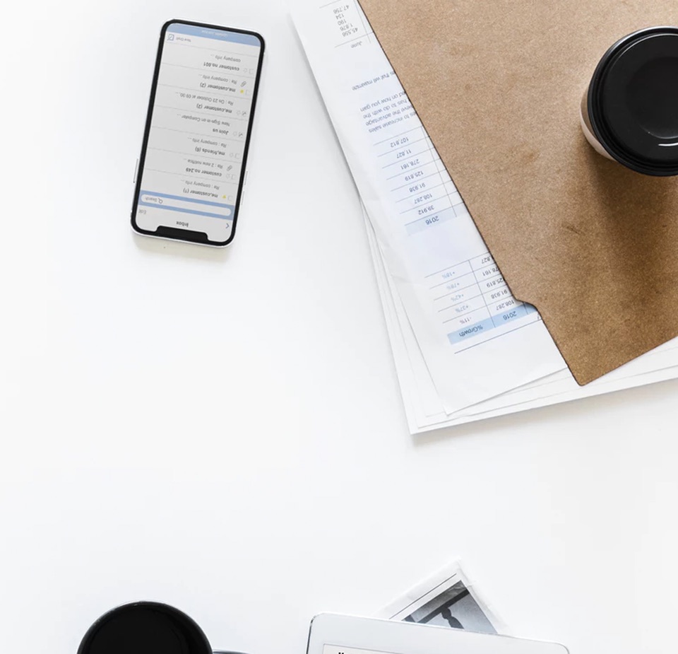 overhead shot of smartphone, file folder and coffee cups on a white table